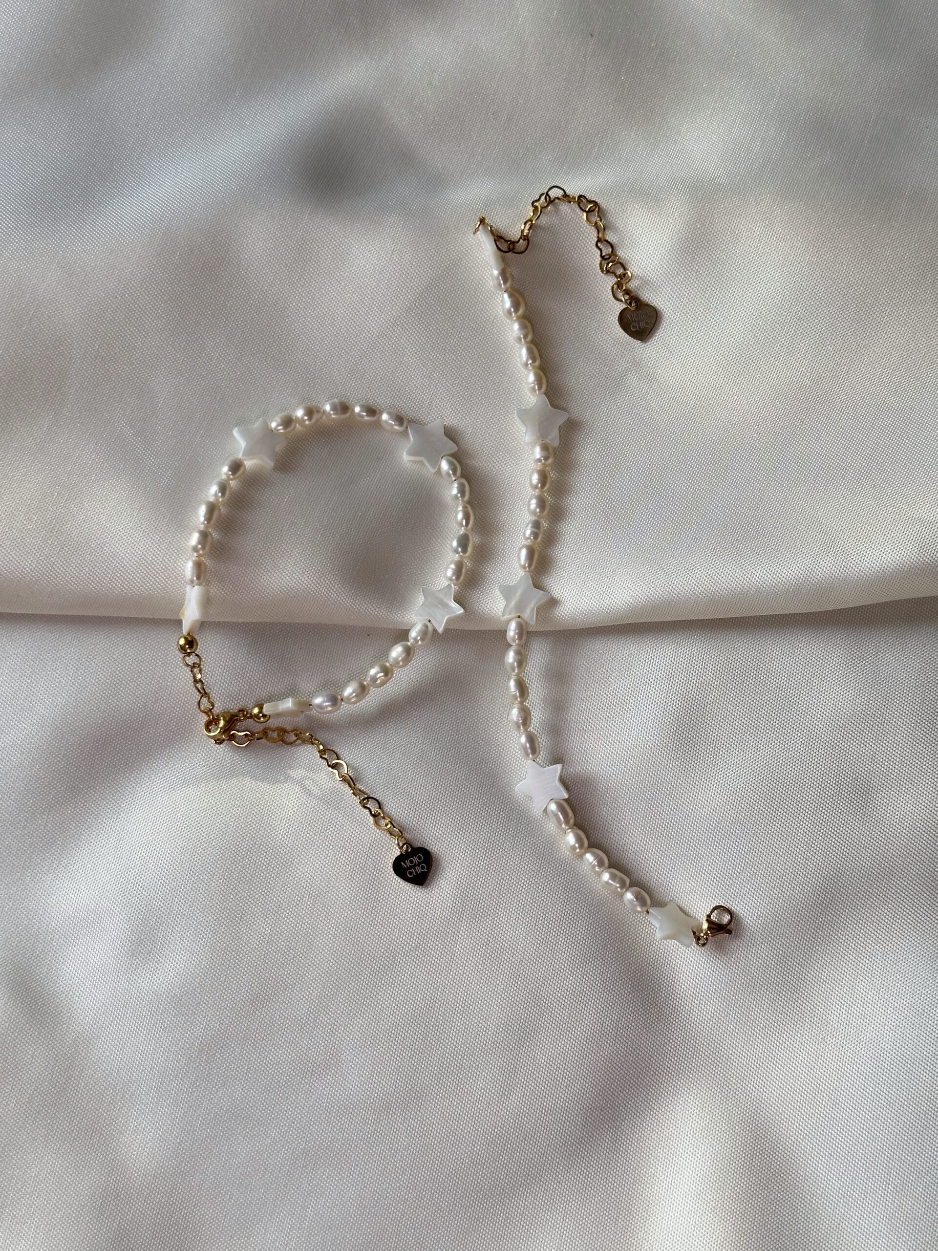 Bracelet with freshwater pearls and star-shaped oyster shell beads, displayed on a soft neutral background in natural lighting.